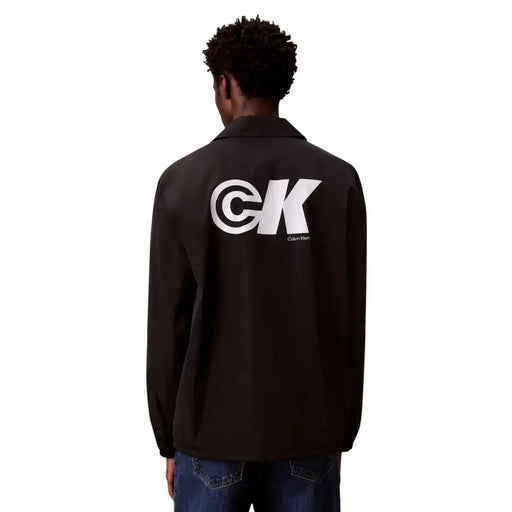 Back view of black calvin klein coach jacket with bold white ck logo in classic polyester blazer style