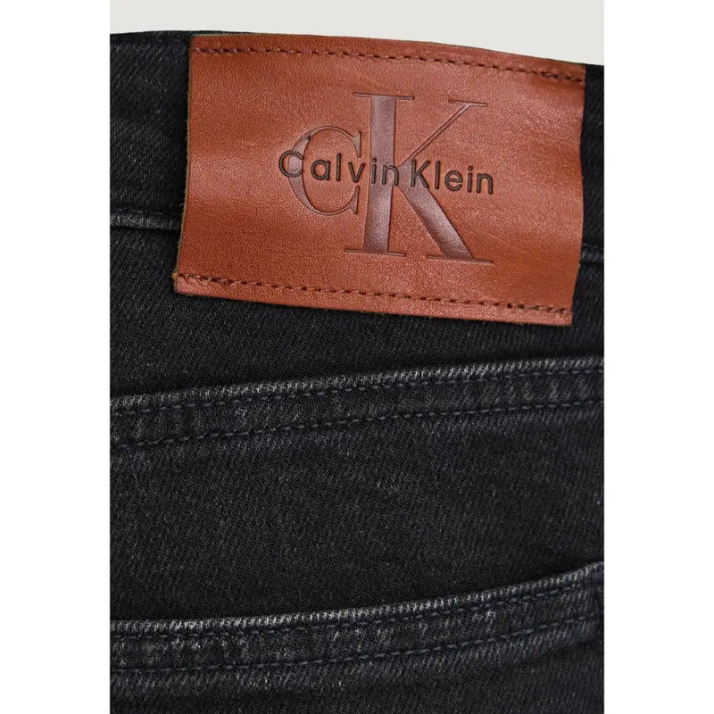 Black cotton denim slim jeans for men showing the back side with tan leather patch featuring calvin klein logo