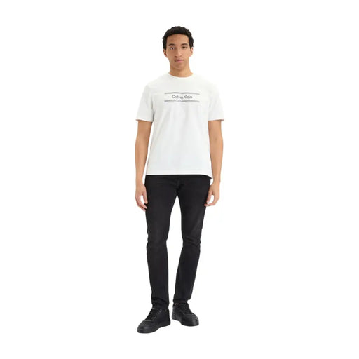 Weißer Calvin Klein t-shirt mit schwarzem Logo und horizontalen Linien, kombiniert mit schwarzen Slim-Jeans aus Baumwoll-Denim für Herren