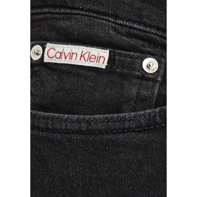 Black cotton denim slim jeans for men featuring a white Calvin Klein label with red lettering and silver rivets