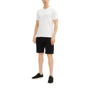 White v-neck t-shirt with black shorts and black sneakers.