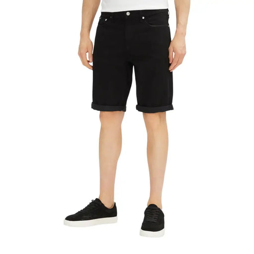 Black denim shorts with rolled hem and button fly design.