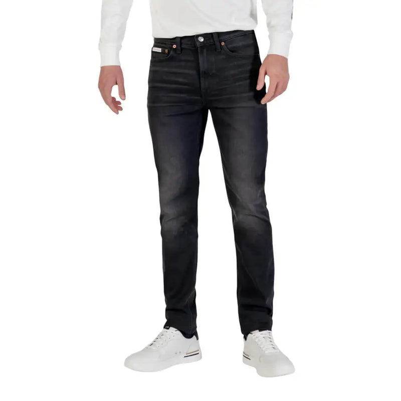 Jean Calvin Klein pour homme, coupe slim, en denim de coton noir, avec délavage subtil, surpiqûres classiques et passants de ceinture.