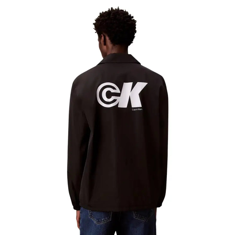 Black Calvin Klein coach jacket showing the back side with a bold white CK logo in Calvin Klein Jeans Men Blazer collection