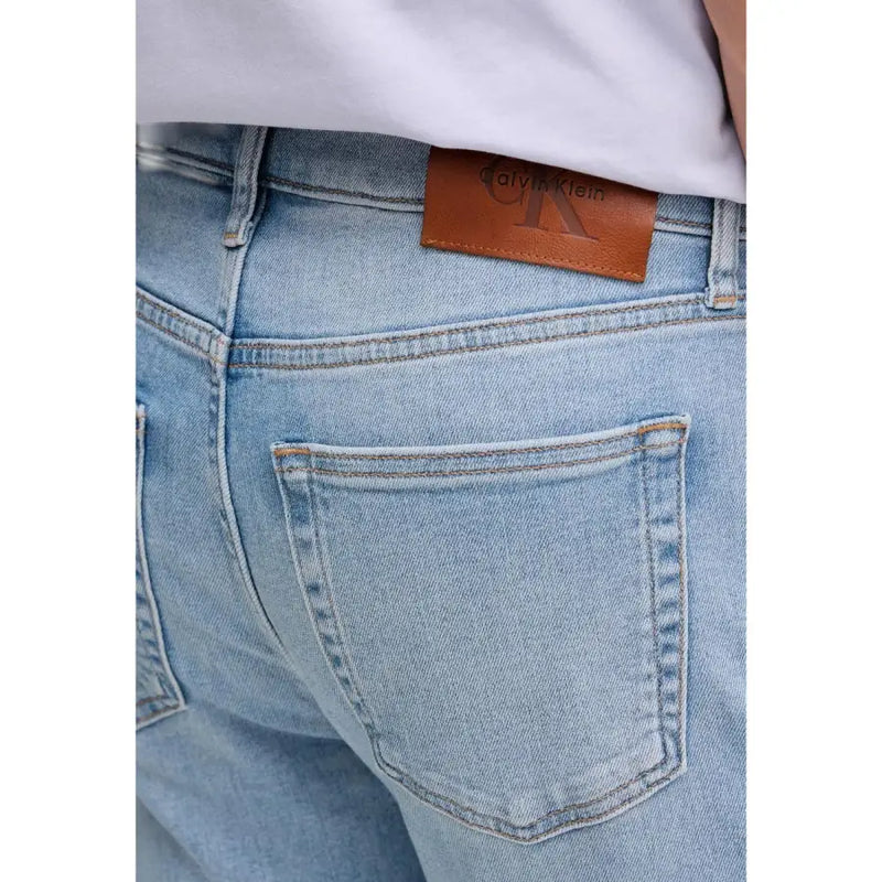 Back view of calvin klein jeans men blue cotton denim jeans with light wash and brown leather brand patch on waistband