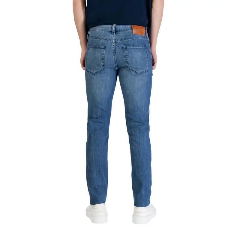 Calvin klein jeans men blue cotton denim jeans slim fit with classic fit and brown leather patch at the waistband back view