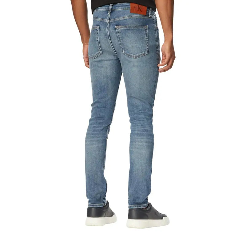 Vue arrière d'un jean Calvin Klein slim fit en denim stretch bleu délavé avec étiquette de marque en cuir marron