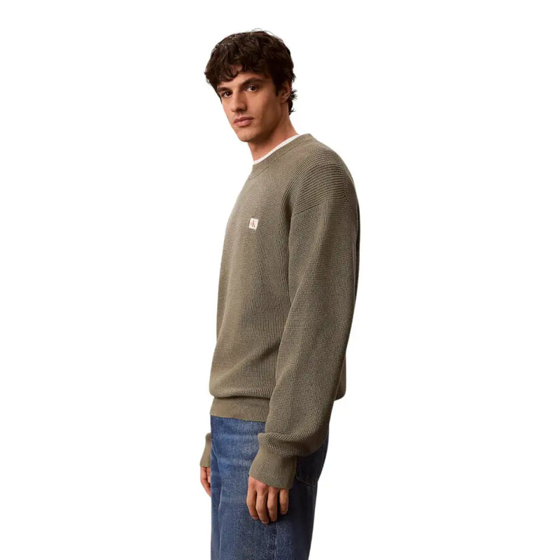 Calvin Klein Jeans Grüner Herrenpullover aus Baumwolle mit Waffelstrick, olivgrüner Struktur und kleinem weißen Logo-Patch auf der Brust