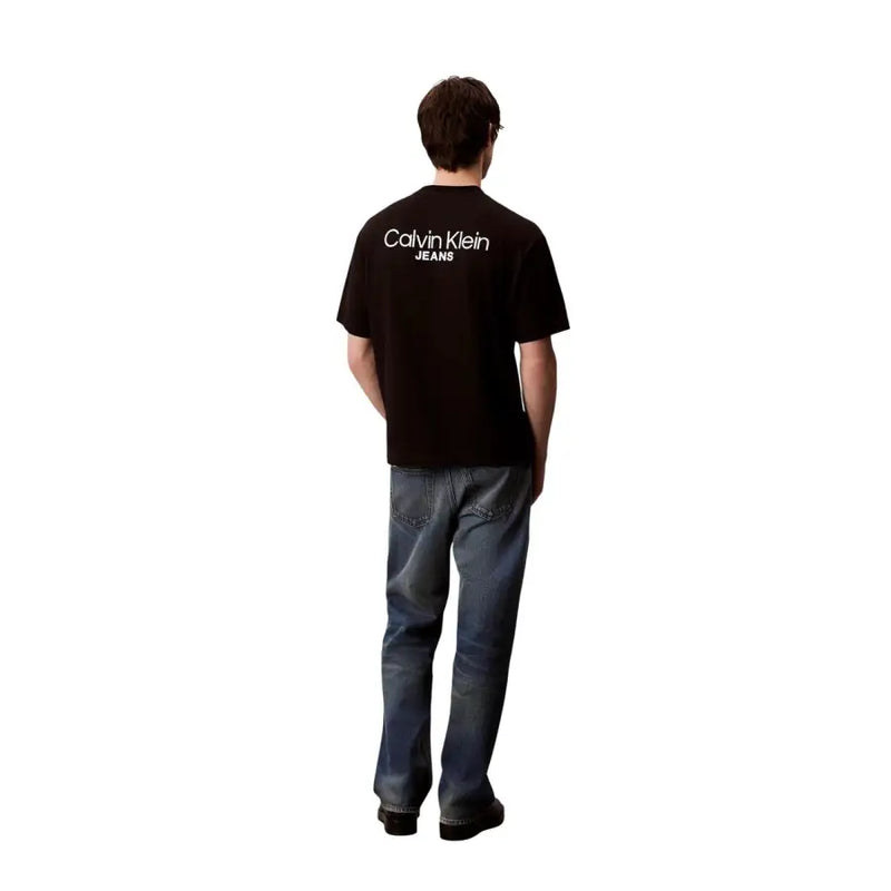 Rückansicht eines schwarzen Calvin Klein Jeans Herren-T-Shirts aus Baumwolle mit weißem Logodruck auf der Rückseite.