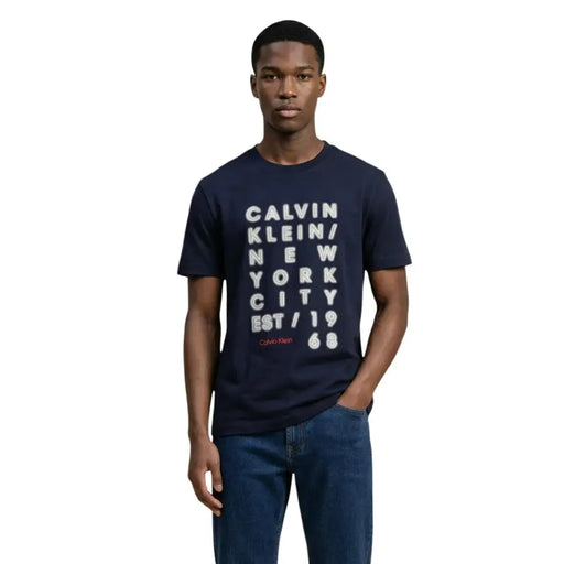 Navy blue Calvin Klein Jeans men t-shirt with bold white vertical text graphic and red brand name script on front