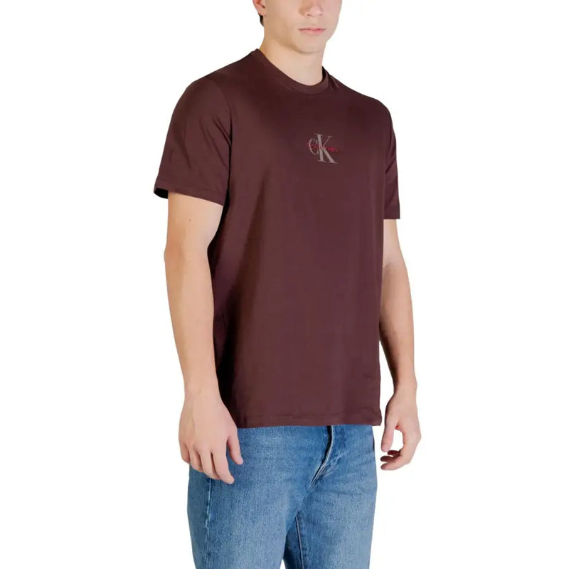 Ein bordeauxrotes Calvin Klein Jeans Herren-T-Shirt aus braun bedruckter Baumwolle mit einem dezenten, gestickten Logo auf der Brust.