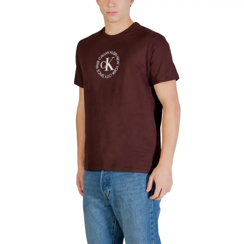Bordeauxrotes Calvin Klein Jeans Herren-T-Shirt aus Baumwolle mit weißem CK-Monogramm-Kreislogo und dem Aufdruck „New York City since 1988“.