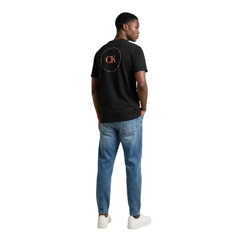 Back side of black Calvin Klein Jeans men t-shirt featuring a pink and white circular logo on the back