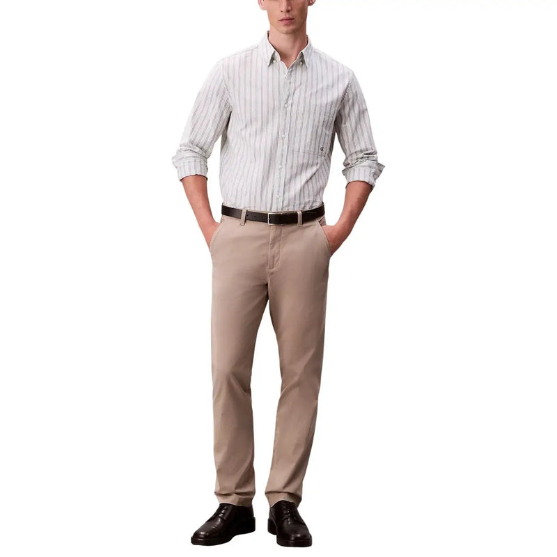 Ein Mann, der beige Chinos mit hochgekrempelten Ärmeln und schwarze Schuhe trägt Calvin Klein Jeans schwarze Baumwoll-Elastan-Hose