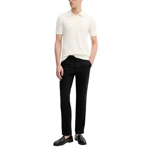 Calvin Klein Jeans Herrenhose kombiniert mit einem cremefarbenen, gerippten Poloshirt mit klassischem Kragen und kurzen Ärmeln