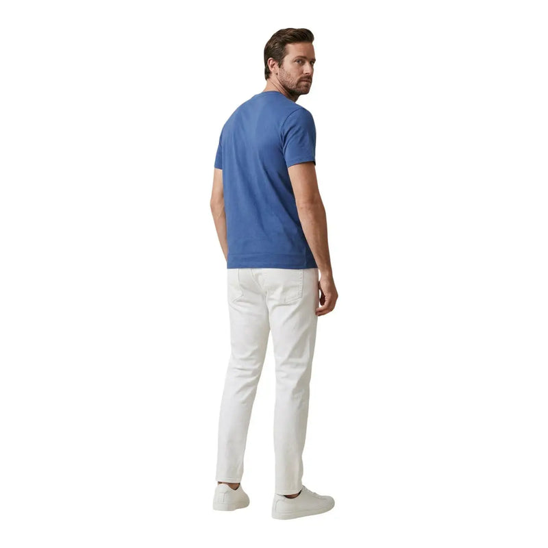 A man wearing white Calvin Klein Jeans men trousers paired with a solid blue short-sleeved t-shirt
