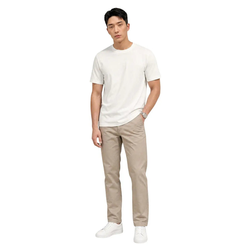 A man wearing calvin klein beige cotton trousers and a plain white short-sleeved t-shirt