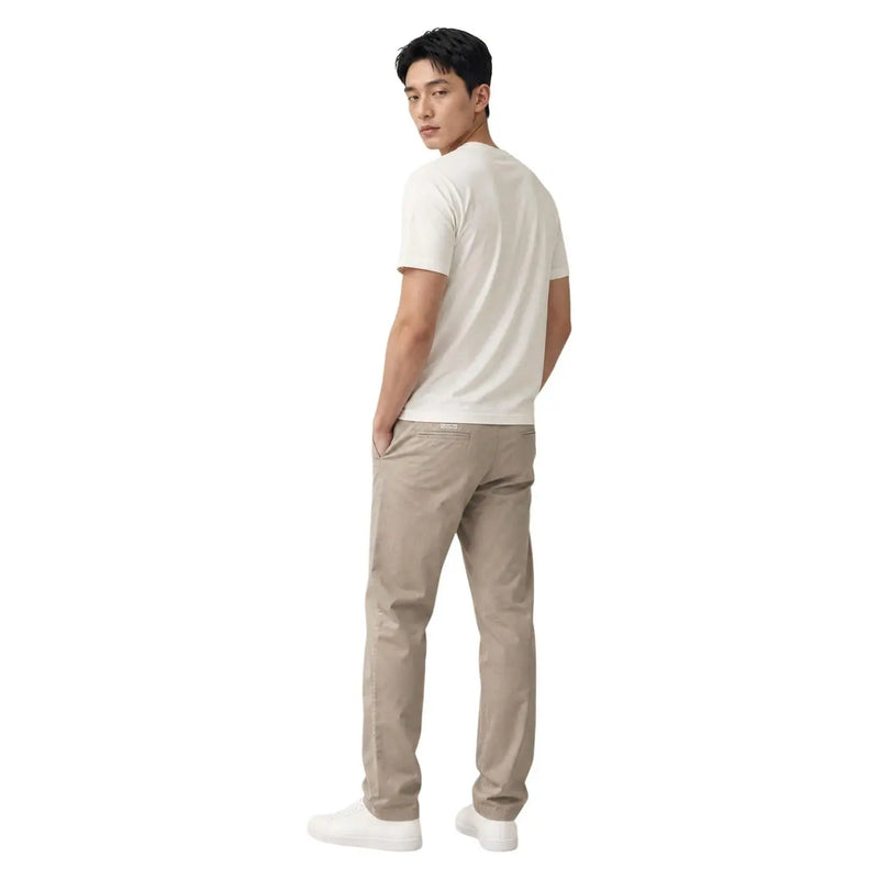 A man wearing beige cotton Calvin Klein trousers and a white t-shirt showing the front side of the product