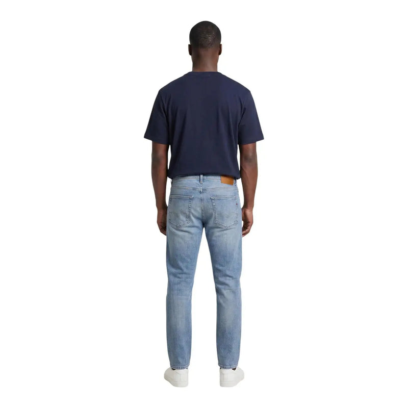 Light-wash denim jeans with classic five-pocket design and brown leather patch on back waistband for casual wear