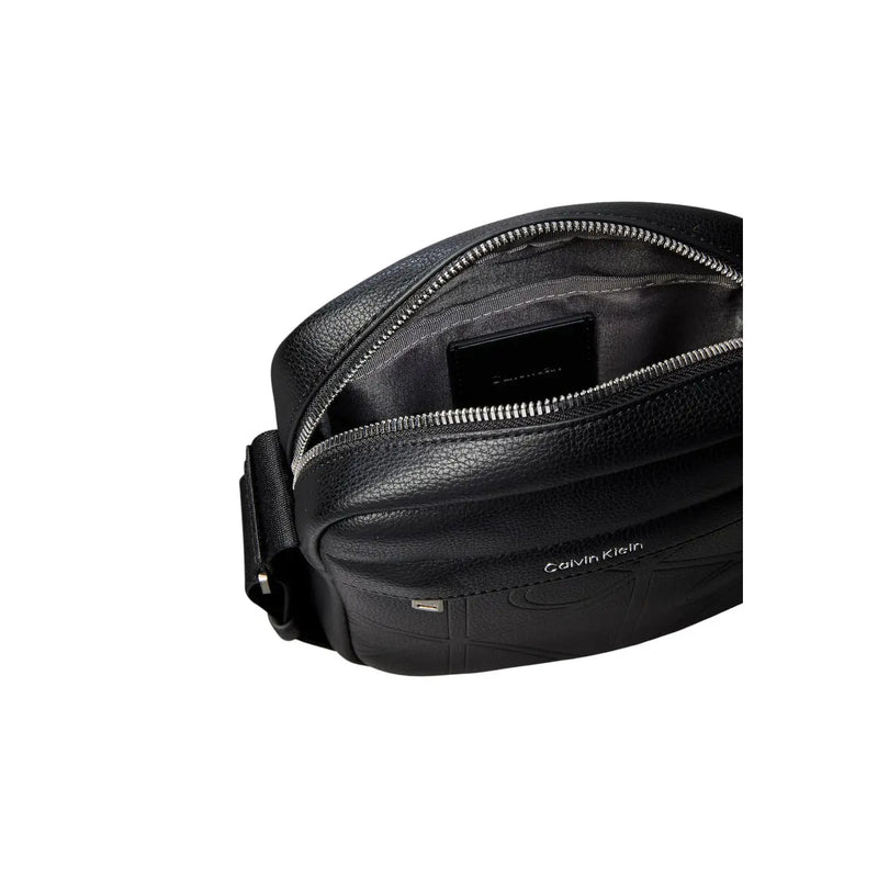 Black calvin klein leather crossbody bag with textured surface and silver zipper for men emblem reporter bag size w16 x h20 cm