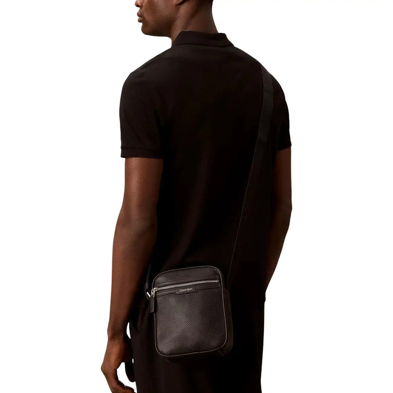 Calvin klein men perforated black leather crossbody bag with silver zipper and brand logo front view