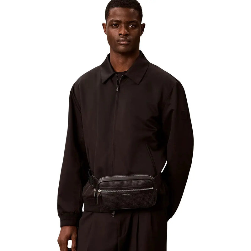 Black textured leather Calvin Klein men perforated waistbag with silver zippers and subtle logo detail in polyurethane