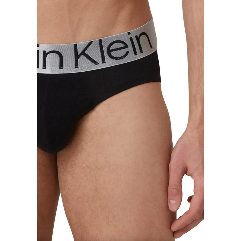 Black Calvin Klein men’s briefs with a gray waistband featuring the brand’s logo in black lettering