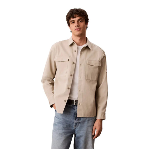 Calvin Klein Chemise beige en coton pour homme, à boutons, avec deux poches poitrine et un discret écusson de marque sur la manche.