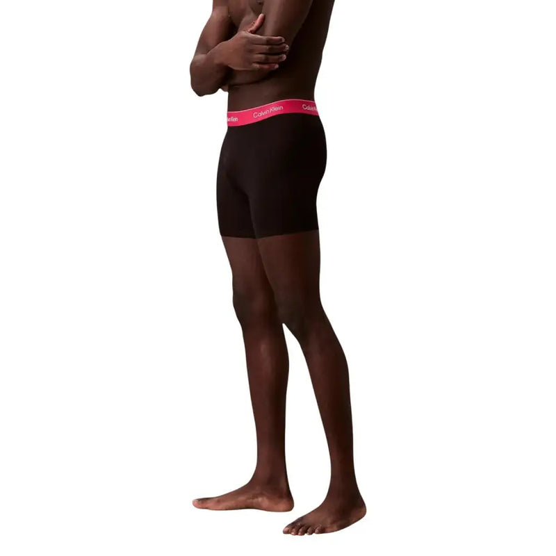 Schwarz Calvin Klein Boxershorts mit leuchtend pinkfarbenem Logo-Bund, entworfen für Komfort und Stil in der Herrenunterwäsche.