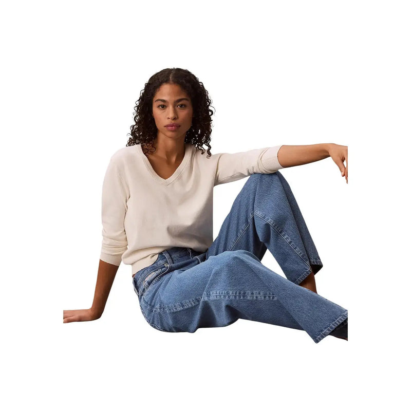 Woman wearing calvin klein women blue cotton denim wide-leg jeans and a cream v-neck sweater front view