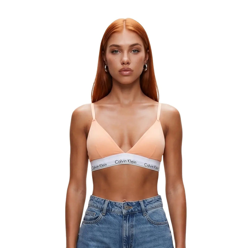 Peach-colored Calvin Klein lightly lined triangle bra with white cotton band featuring black logo text