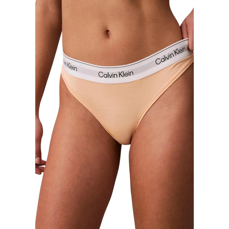 Beige calvin klein polyester thong underwear with white waistband and black calvin klein branding visible from the back