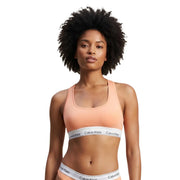 Peach-colored Calvin Klein women unlined bralette sports bra with white logo band made from grey cotton modal