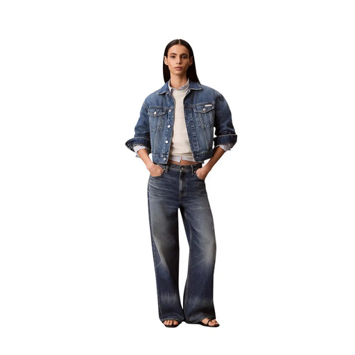 A woman wearing a dark-wash denim jacket with rolled-up sleeves and wide-leg jeans with calvin klein white cotton sweatshirt