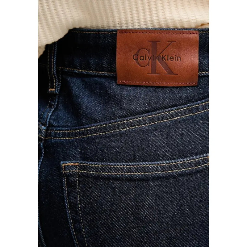 Dark blue cotton denim jeans for women with brown leather calvin klein patch on waistband fall winter style back view