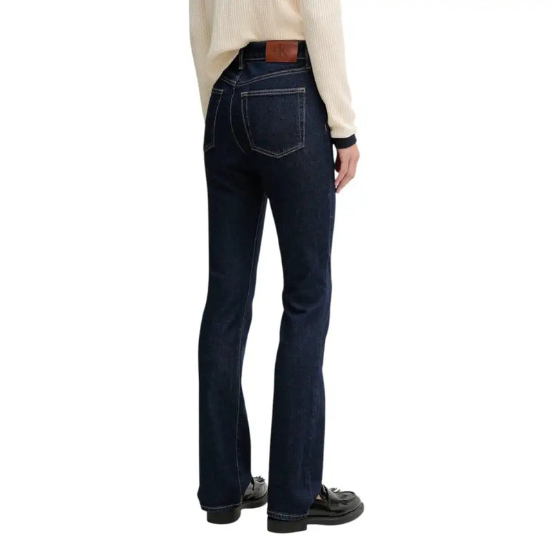 Calvin Klein women’s blue cotton jeans with dark indigo denim flare, brown leather belt loop, and white stitching