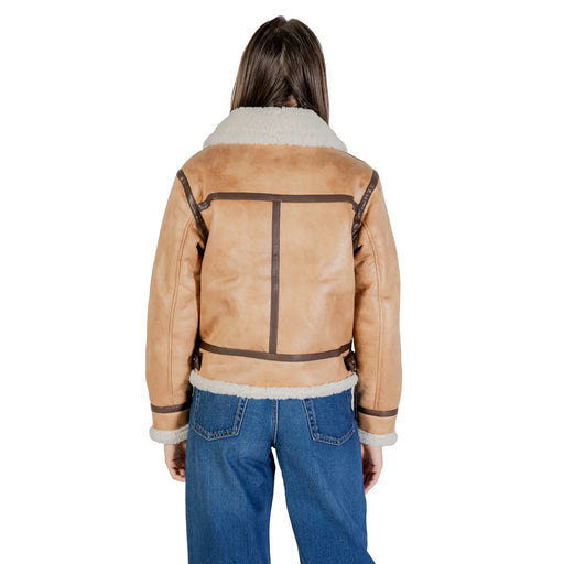 Bomberjacke aus hellbraunem Shearling mit flauschigen weißen Fleecekragen und -bündchen sowie dunkelbraunem Lederbesatz, kombiniert mit einem beigen Polyesterblazer.