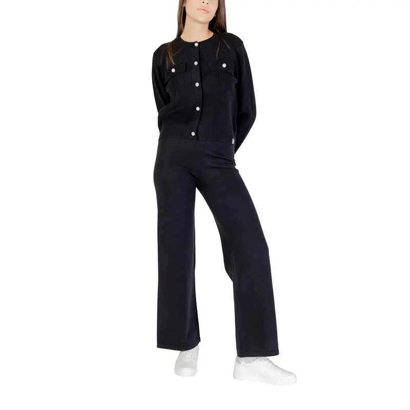 Black knit cardigan with white buttons and front pockets worn with choral women trousers black viscose blend fall winter
