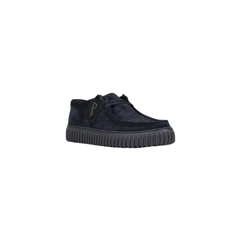 Schwarze Schnürstiefel aus Wildleder von Clarks für Herren, dazu ein dunkelblauer Wildleder-Slipper und eine gerippte Gummisohle.
