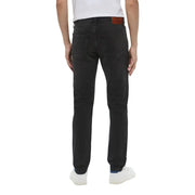 Back view of dark wash black denim jeans by calvin klein featuring a brown leather brand patch on the waistband