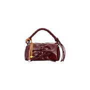 A glossy burgundy Desigual women bag featuring a braided handle, bow front closure, tassel details, and inside pocket