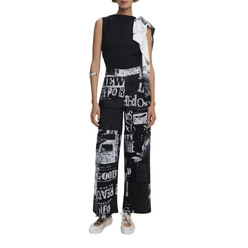 Black and white sleeveless jumpsuit with newsprint pattern and front zip detail