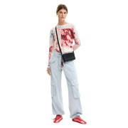 Black textured crossbody bag with visible logo paired with desigual pink floral long sleeve round neck viscose knitwear