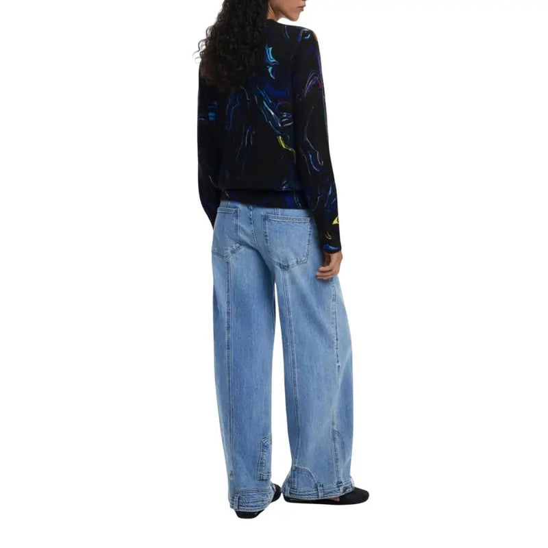 Woman wearing Desigual black long-sleeve knitwear with colorful abstract patterns and light-wash wide-leg jeans