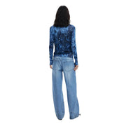 Woman wearing a blue floral long cardigan with long sleeves and wide-leg jeans