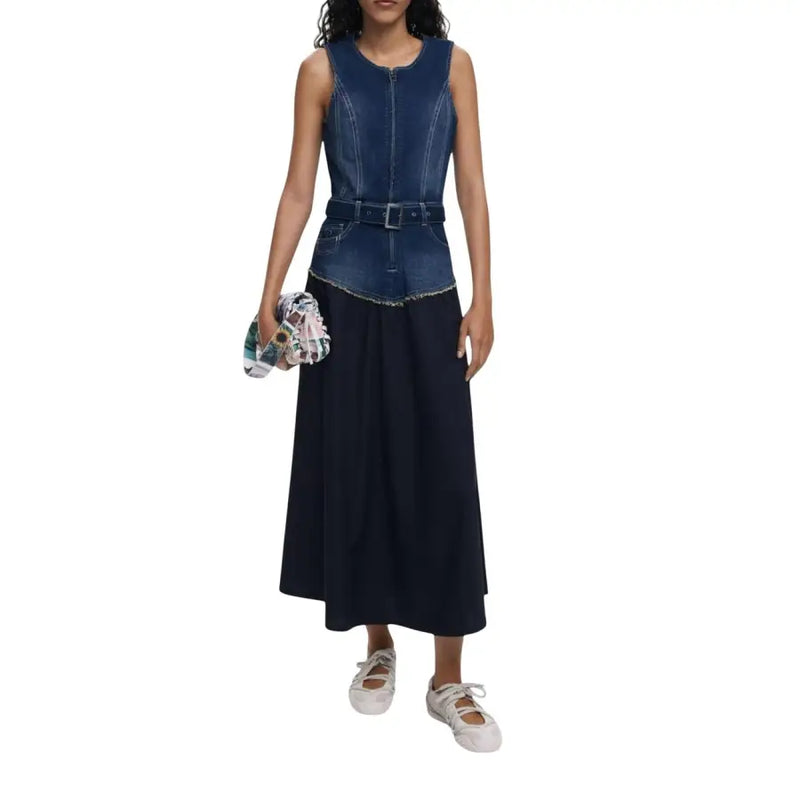Women wearing a two-tone denim and black maxi dress with belt and multicolored clutch