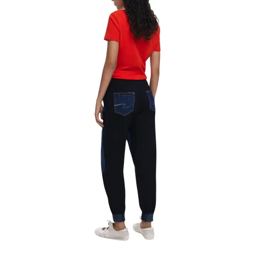 Women wearing a red short-sleeved top and black joggers with denim accents for Desigual Women Fall Winter Blue Jeans
