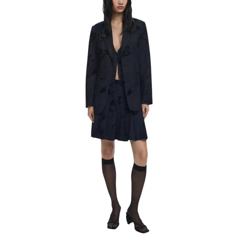 Woman wearing Desigual floral black long blazer with dark blue skirt sheer knee-high socks and open-toed block heels