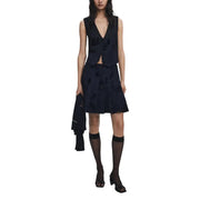 Woman wearing a dark blue sleeveless vest and floral black skirt with knee-high sheer socks and black open-toed heels for Fall Winter fashion