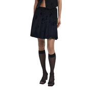 Black knee-length skirt with floral embroidery paired with sheer knee-high socks and open-toed heels